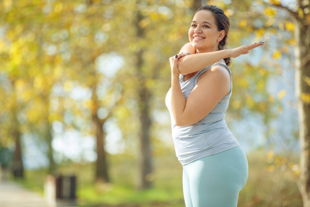 A woman with an autoimmune disease smiling and stretching