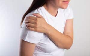 A woman with rotator cuff pain holding her shoulder