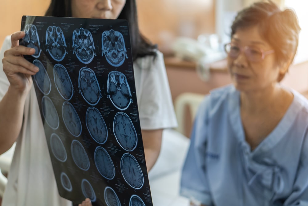 A doctor showing a woman with a neurodegenerative disease brain scans