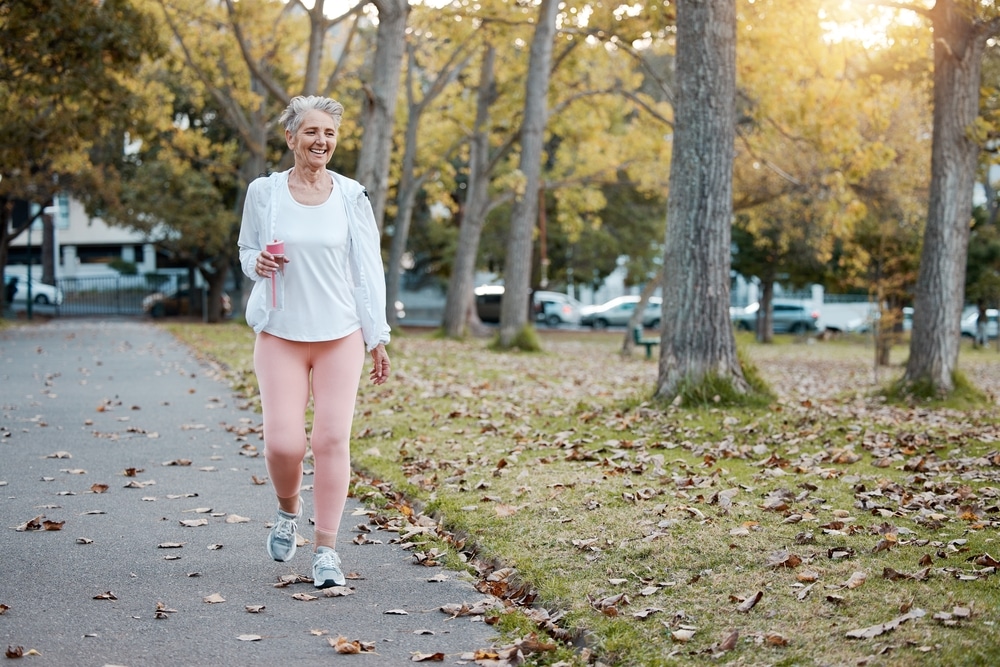 A senior woman with a neurodegenerative disease walking outdoors after stem cell therapy