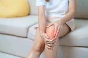 A woman with joint pain holding her knee