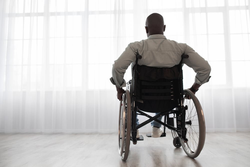 A man with ALS sitting in a wheelchair and looking out the window
